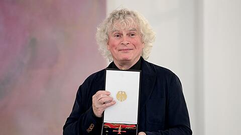Sir Simon Rattle zeigt seine Auszeichnung.