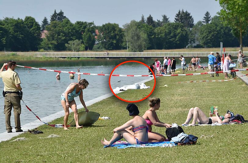 Polizisten sperren am Dienstag den Bereich um die gefundene Leiche am Riemer See ab. Die restlichen Badegäste scheint das nicht zu stören.