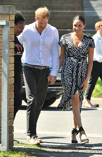 Im Herbst 2019 gehen Herzogin Meghan und Prinz Harry erstmals mit Sohn Archie auf Familienreise nach Afrika. Nur wenige Stunden nach der Landung besucht das royale Paar die Township Nyanga. Die Herzogin erscheint zu diesem Termin in einem gemusterten Wickelkleid von einem nachhaltigen Label aus Malawi.