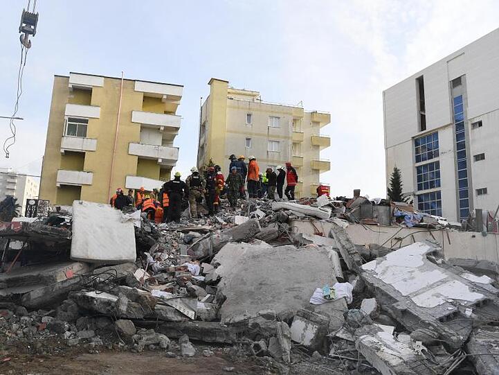 Rettungskräfte stehen auf den Trümmern eines eingestürzten Gebäudes. Bei dem schwersten Erdbeben seit Jahrzehnten kamen in Albanien mindestens 49 Menschen ums Leben.