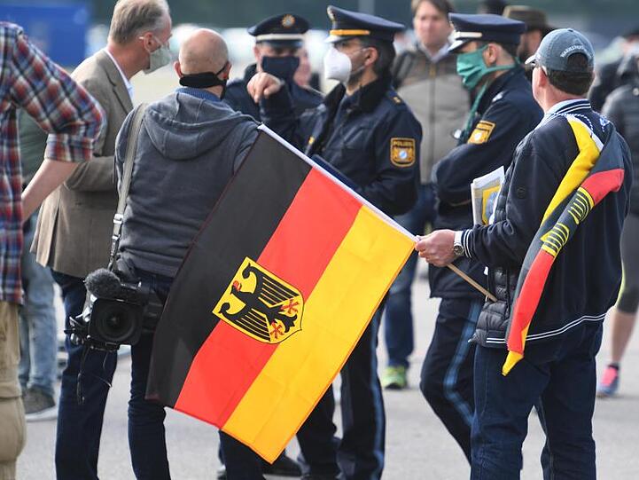 Ein Demonstrant gegen die Corona-Maßnahmen mit Deutschlandflagge auf der Theresienwiese. Foto: Felix Hörhager/dpa