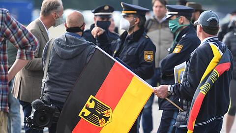Ein Demonstrant gegen die Corona-Maßnahmen mit Deutschlandflagge auf der Theresienwiese. Foto: Felix Hörhager/dpa