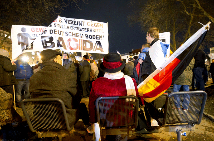 Eine Frau mit Hut und Deutschlandflagge sitzt am 12.01.2015 in München (Bayern) am Rande einer Demonstration der islamfeindlichen Vereinigung "Bagida" auf einer Bank