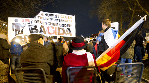 Eine Frau mit Hut und Deutschlandflagge sitzt am 12.01.2015 in München (Bayern) am Rande einer Demonstration der islamfeindlichen Vereinigung "Bagida" auf einer Bank