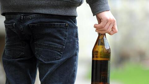 Ein Jugendlicher hält eine geöffnete Bierflasche in der Hand.