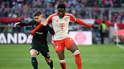 Bayerns Alphonso Davies (r) und Bremens Romano Schmid kämpfen um den Ball.