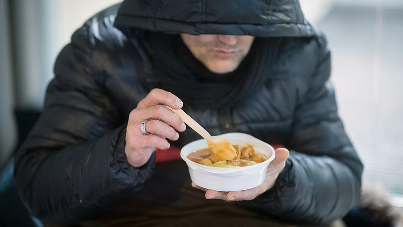 Ein Obdachloser isst in der Nähe des Stachus eine warme Mahlzeit, die er von den Helfern des Kältebusses erhalten hat.
