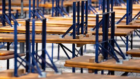 Menschenleer zeigt sich ein Biergarten mit gestapelten Bänken und Tischen im Westpark in München.