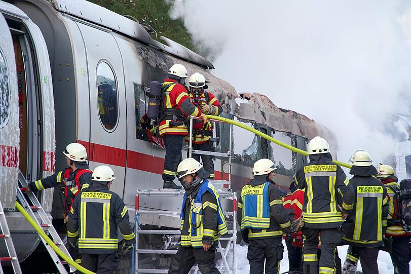 Feuerwehrleute löschen den brennenden ICE-Wagen, der auf der Schnellstrecke zwischen Frankfurt und Köln Feuer gefangen hatte.
