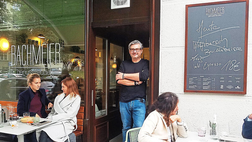 Sichtlich glücklich über sein neues Restaurant: Spitzenkoch Hans Jörg Bachmeier (Mitte) vor dem holzvertäfelten Eingang, der vom Vorgänger-Lokal erhalten blieb.