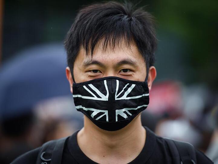 Ein Demonstrant trägt auf dem zentralen Ort der Kundgebung im Victoria Park einen Mundschutz mit der britischen Flagge.