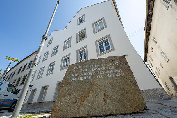 Ein Stein mit der Aufschrift "F&uuml;r Frieden, Freiheit und Demokratie. Nie wieder Faschismus, Millionen Tote mahnen" steht vor dem neuen Polizeizentrum im Hitler-Geburtshaus.