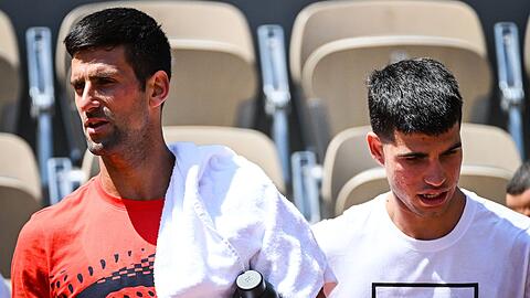 Novak Djokovic (l) aus Serbien und Carlos Alcaraz aus Spanien gehen nebeneinander während einer Trainingseinheit für die French Open 2023.