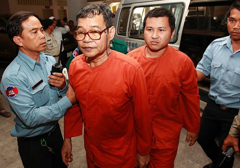 Khmer Krom-Aktivisten werden von einem kambodschanischen Polizisten bewacht, wie sie am Amtsgericht in Phnom Penh, Kambodscha, eintreffen. Das Gericht verurteilte die Aktivisten der Khmer Krom (Süd-Vietnam) zwischen 5 und 9 Jahren Gefängnis, die angeblich an dem Sturz der kambodschanischen Regierung beteiligt gewesen waren.