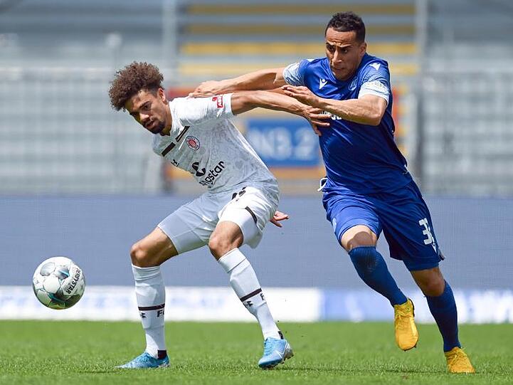 Luis Coordes (l) vom FC St. Pauli schirmt den Ball gegen Änis Ben-Hatira ab.