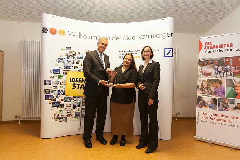 Stefan Witte von der Deutschen Bank und Katrin Hennig vom Land der Ideen (r.) gratulieren der Einrichtungsleiterin Renate Schemann.
