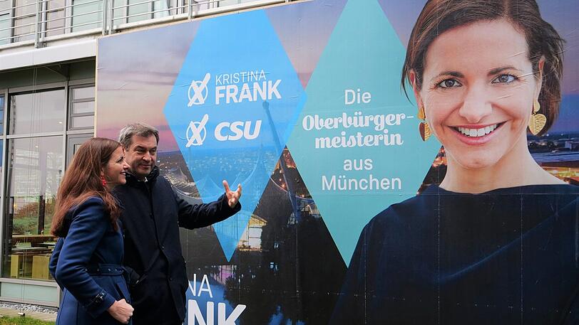 Markus Söder hält kurz inne vor einem Wahlplakat mit der OB-Kandidatin der CSU, Kristina Frank.