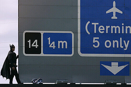 Ein Mann im Batmankostüm klettert auf ein Autobahnschild nahe London. Er will für die Rechte von Vätern demonstrieren.