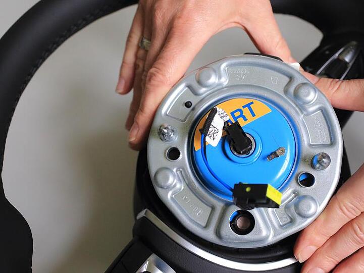 Ein Zünder für Airbags wird in ein Auto-Lenkrad eingesetzt. Foto: Jens Wolf/Archivbild