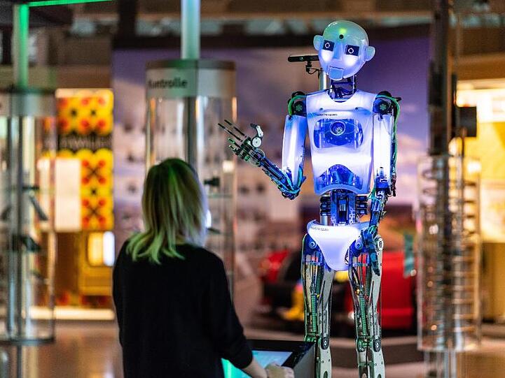 Eine Frau steht in der Ausstellung: "Künstliche Intelligenz und Robotik" im Heinz Nixdorf Museumsforum vor dem Roboter "robothespian".