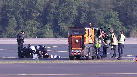 Sicherheitspersonal und Polizisten versuchen am Düsseldofer Flughafen, Aktivisten vom Asphalt auf dem Rollfeld zu lösen.