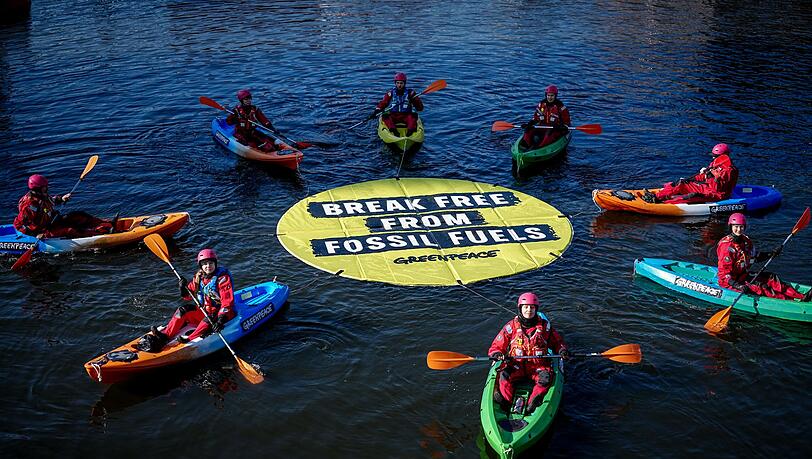 Greenpeace fordert bei einer Aktion am Veranstaltungsort die Abkehr von fossilen Energien.