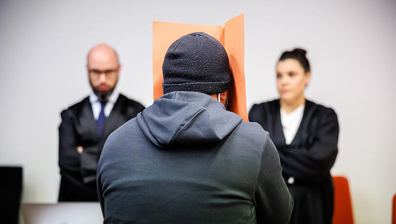 Der Angeklagte (mi.) sitzt zu Prozessbeginn in einem Gerichtssaal vom Landgericht München II vor seinen Anwälten Francesca Rossiello-Bianco (re.) und Deniz Aydin und verdeckt sein Gesicht. Der 39 Jahre alte Mann ist wegen Vergewaltigung, gefährlicher Körperverletzung und Freiheitsberaubung angeklagt – unter anderem, weil er bei Rollen- und Fesselspielen das sogenannte "Safeword" einer Frau ignoriert und weitergemacht haben soll. Der Angeklagte (mi.) sitzt zu Prozessbeginn in einem Gerichtssaal vom Landgericht München II vor seinen Anwälten Francesca Rossiello-Bianco (re.) und Deniz Aydin und verdeckt sein Gesicht. Der 39 Jahre alte Mann ist wegen Vergewaltigung, gefährlicher Körperverletzung und Freiheitsberaubung angeklagt – unter anderem, weil er bei Rollen- und Fesselspielen das sogenannte "Safeword" einer Frau ignoriert und weitergemacht haben soll.