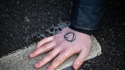 Ein Klimaaktivist hat sich mit der Hand auf den Asphalt geklebt.