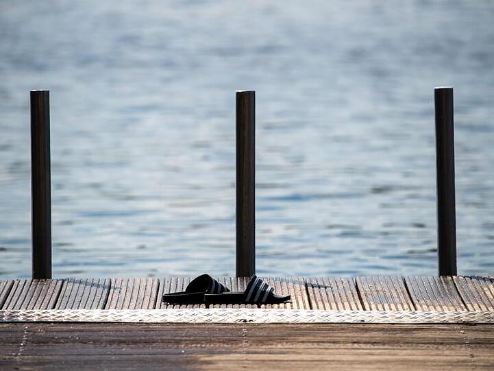 Badeschuhe stehen auf einem Steg am bayrischen Rothsee. Nach einem teils gewittrigen Wochenstart beruhigt sich das Wetter am Dienstag wieder ein wenig.