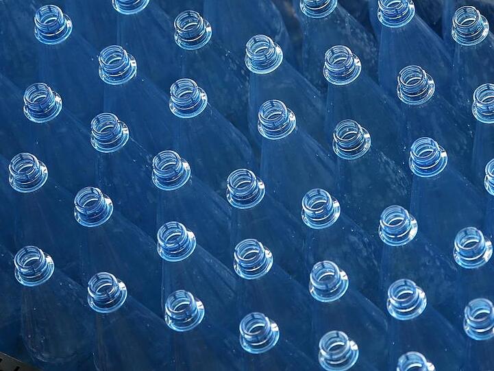 Leere PET-Mehrwegflaschen für Mineralwasser stehen auf einem Transportband einer Abfüllanlage.