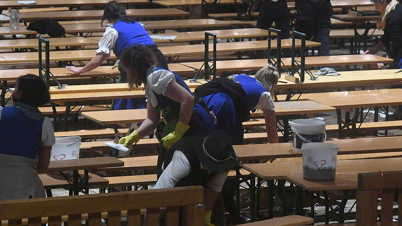 Nach dem Kehraus putzen die Wiesn-Bedienungen die Tische und räumen im Zelt auf.