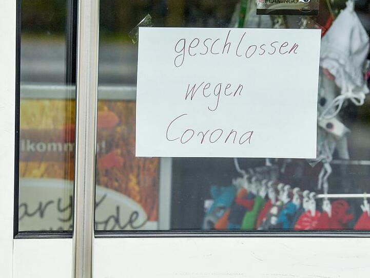 Ein Zettel mit der Aufschrift "geschlossen wegen Corona" klebt an der Tür eines Geschäfts.