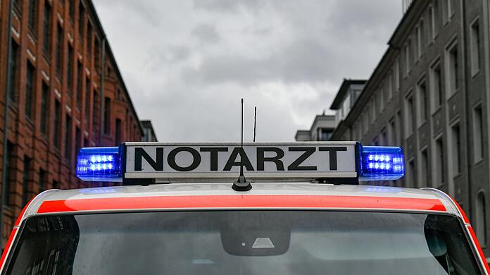 Ein Notarztwagen steht mit eingeschaltetem Blaulicht auf der Straße.