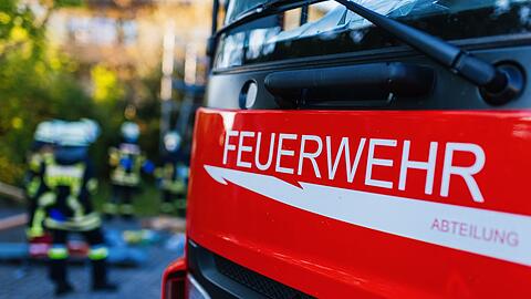 Feuerwehrleute stehen hinter einem Einsatzfahrzeug.