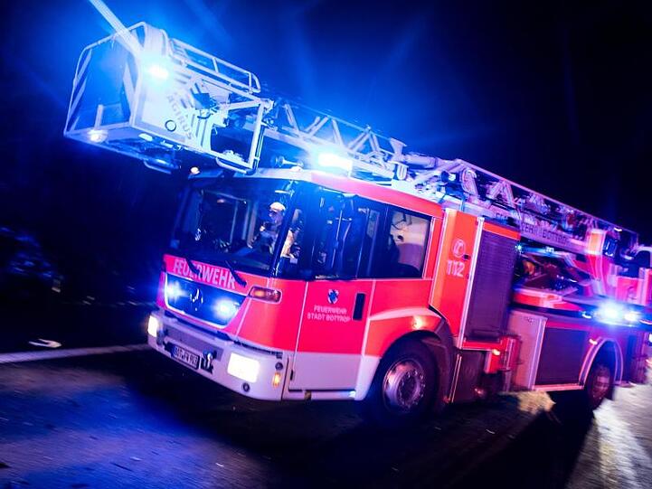 Ein Drehleiterwagen der Feuerwehr fährt während eines Einsatzes über eine Straße. Foto: Marcel Kusch/Archivbild