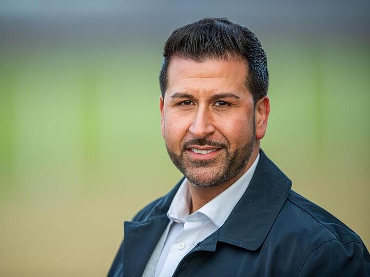 Ozan Iyibas, Bürgermeisterkandidat der CSU, steht an einem Feld. Foto: Lino Mirgeler/dpa/Archivbild