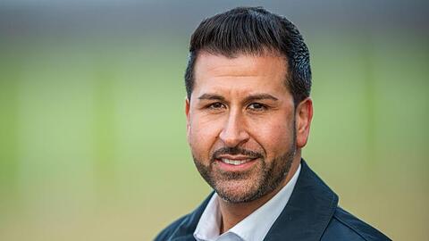 Ozan Iyibas, Bürgermeisterkandidat der CSU, steht an einem Feld. Foto: Lino Mirgeler/dpa/Archivbild