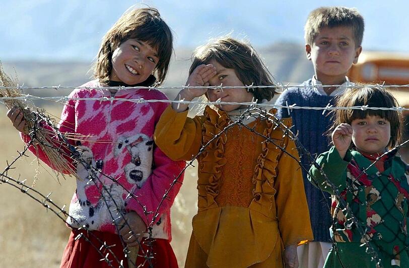 2002: Afghanische Mädchen stehen an einem Zaun, der die deutsche Basis umgibt.