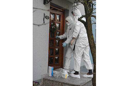 Experten der Spurensicherung betreten in weißen Schutzanzügen das Haus der Familie R., in dem das furchtbare Blutbad stattfand.