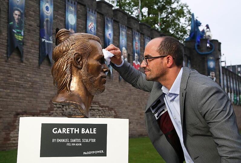 Emanuel Santos putzt in Cardiff (Großbritannien) die Büste des Fußballspielers von Real Madrid Gareth Bale.