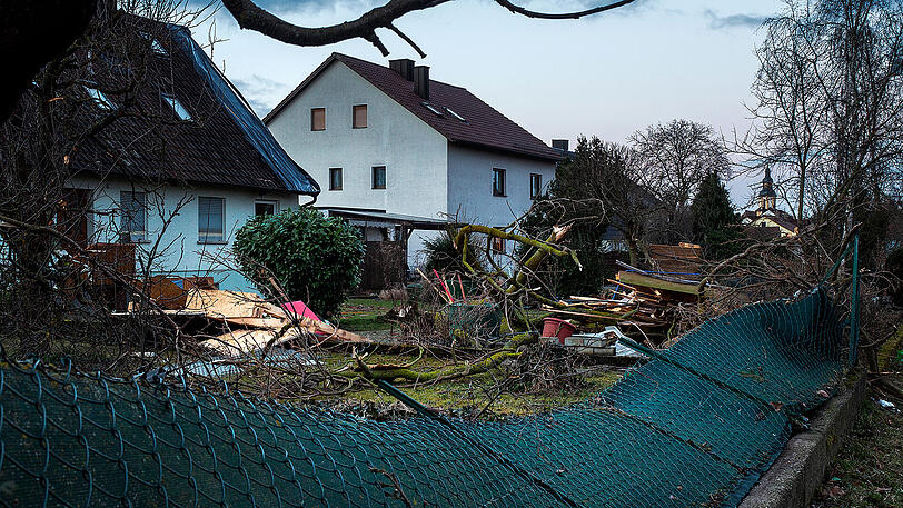 Völlig zerstörte Gärten und ein entwurzelter Baum sind bei Morgendämmerung in Kürnach (Bayern) zu sehen. Eine Windhose, auch als Tornado bezeichnet, hatte am Vortag erhebliche Schäden in der unterfränkischen Ortschaft angerichtet. Zahlreiche Häuser und Lauben waren durch den Sturm zu Schaden gekommen. Verletzt wurde niemand.