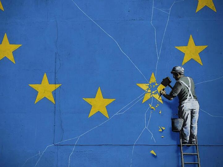 So sieht es der wohl bekannteste unbekannte Künstler der Welt: Das Brexit-Wandbild von Banksy zeigt einen Mann, der einen Stern aus der EU-Flagge heraushämmert.