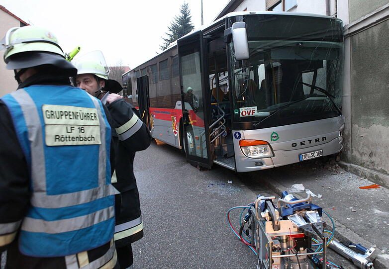 Feuerwehrleute stehen am Montag neben einem verunglückten Linienbus in Hemhofen