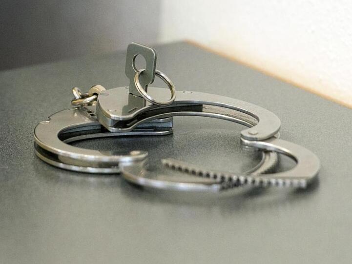 Handschellen liegen auf einem Tisch. Foto: Armin Weigel/dpa/Symbolbild
