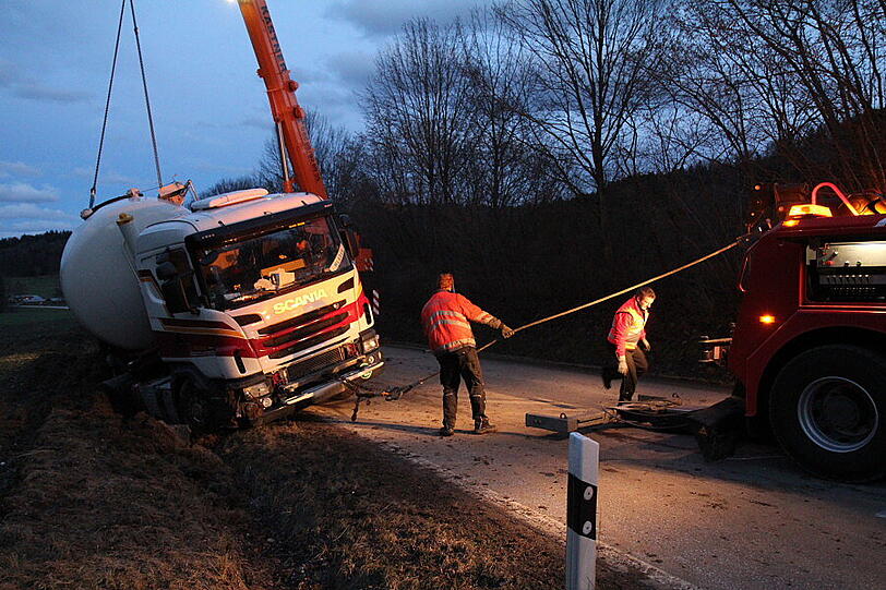 Ein Bergungsfahrzeug und zwei Kräne werden benötigt um den vollbeladenen LKW wieder auf die Straße zu ziehen.