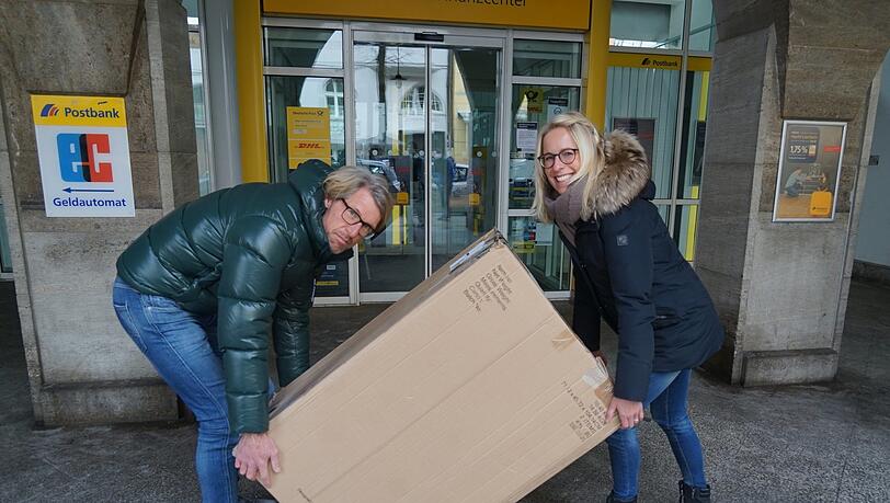 Markus Liegmann kann nicht darüber lachen, dass die Post an der Agnesstraße geschlossen ist, seine Partnerin nimmt es mit Humor. Die schwere Kiste muss wieder heim.