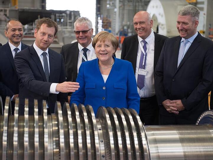 Bundeskanzlerin Angela Merkel steht zusammen mit Sachsens Ministerpräsident Michael Kretschmer (l) im Siemens-Werk in Görlitz.