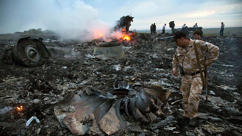 Menschen gehen im Juli 2014 durch die Trümmer an der Absturzstelle des Passagierflugzeugs MH17 in der Nähe des Dorfes Grabovo in der Ostukraine.