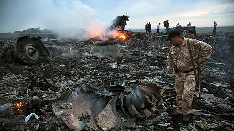 Menschen gehen im Juli 2014 durch die Trümmer an der Absturzstelle des Passagierflugzeugs MH17 in der Nähe des Dorfes Grabovo in der Ostukraine.