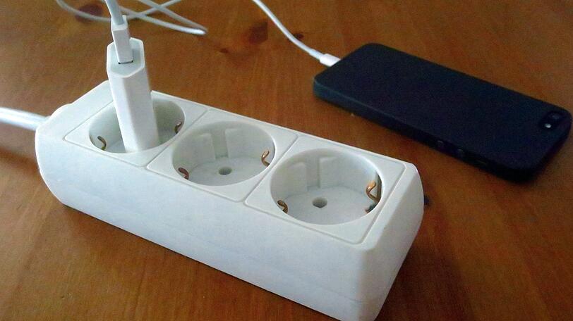 Ein Smartphone saugt an der Steckdose &ndash; ohne Strom geht nichts. (Symbolbild)